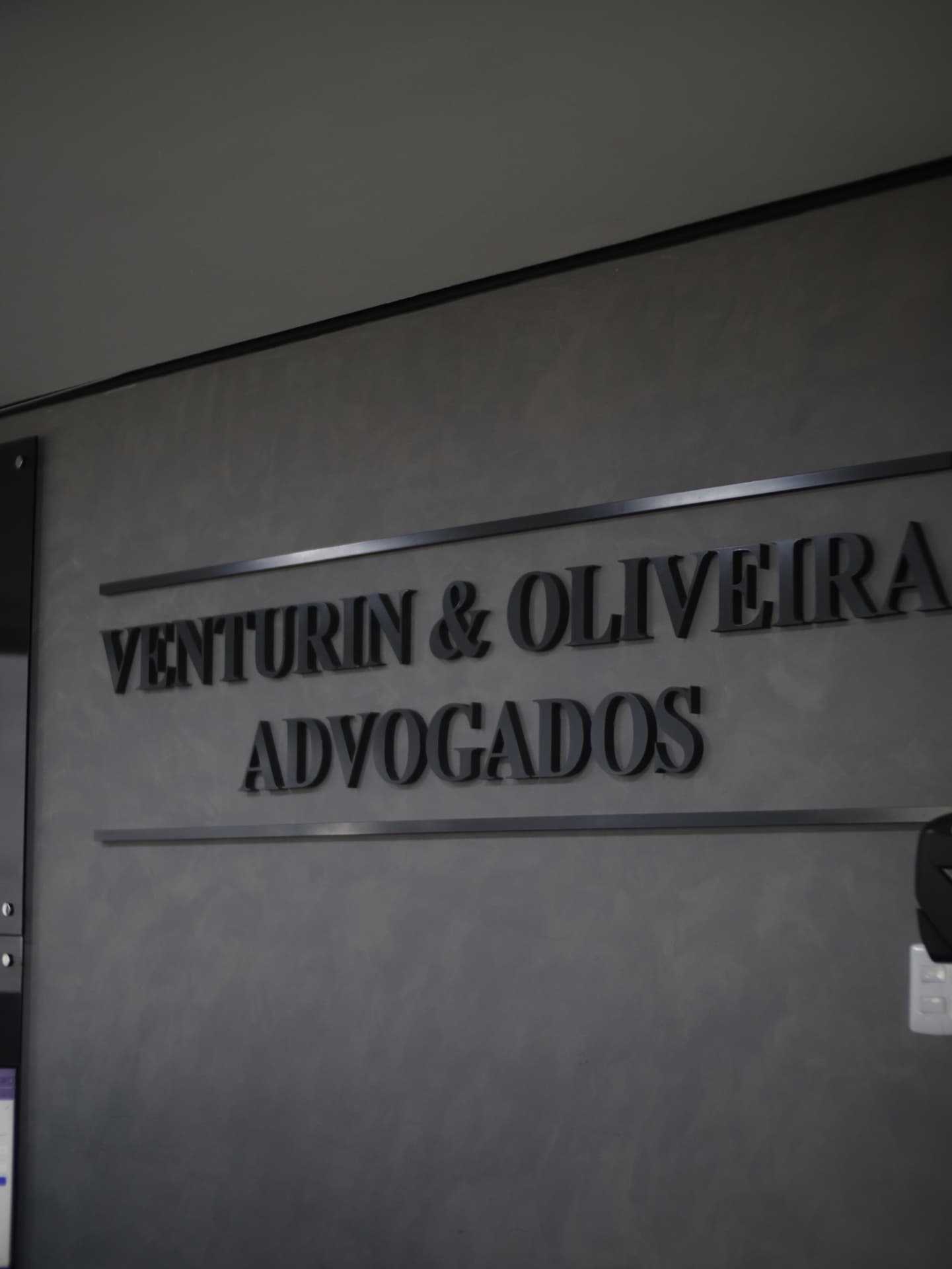 Letreiro na parede do escritório com o nome Venturin & Oliveira Advogados